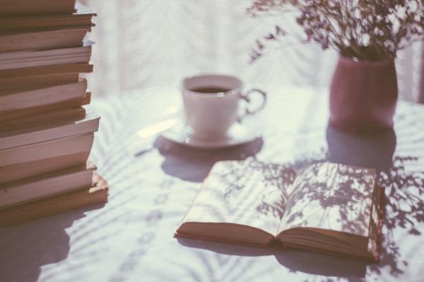 A cup of tea and a pile of books on a table